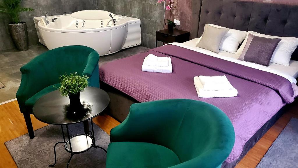 a bedroom with a bed and two chairs and a tub at Restoran Orijent 5 in Sombor