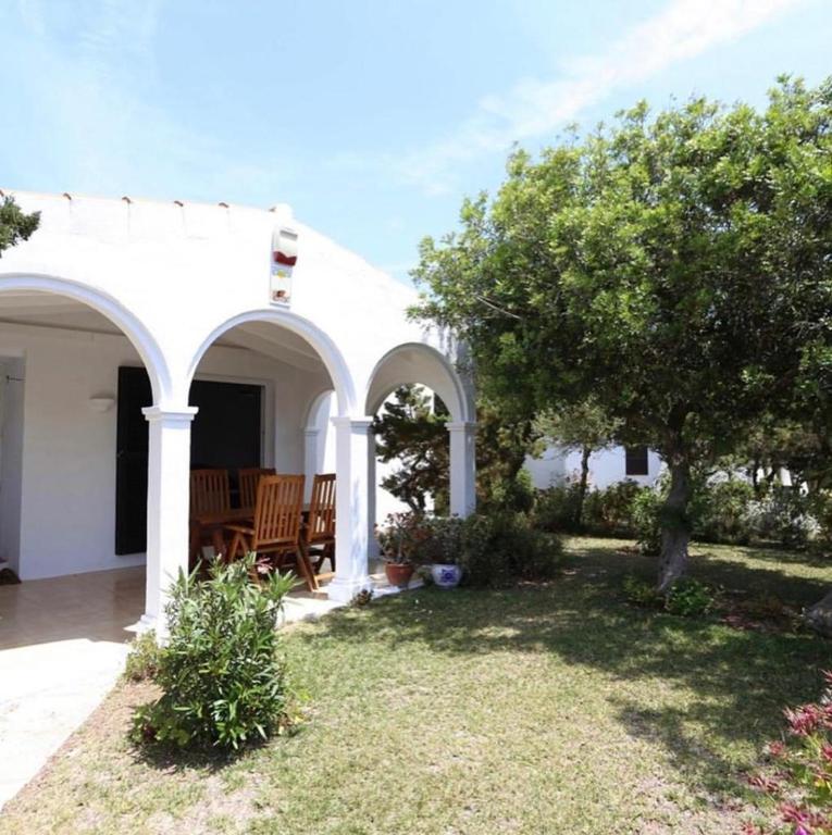 a white house with a table and a tree at Grupoandria Villa Julia in Cala en Forcat