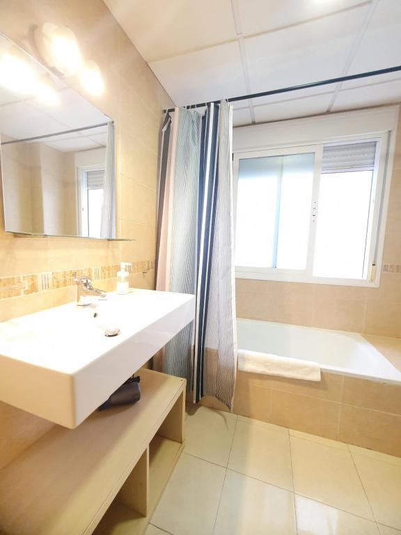 une salle de bain avec un lavabo, une baignoire et un miroir dans l'établissement Ático centro "El diván azul", à Malaga