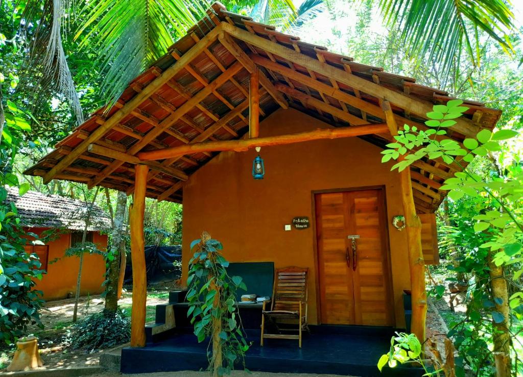 ウダワラウェにあるSandalwood Cottageの木造屋根の小さなオレンジ色の家