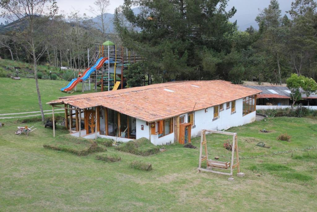 une petite maison dans un champ avec une aire de jeux dans l'établissement Hotel Mi Villa, à Guasca