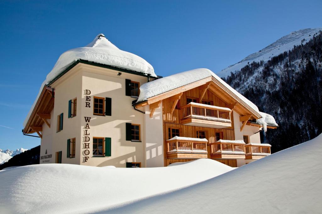 un bâtiment avec de la neige devant lui dans l'établissement Der Waldhof, à Sankt Anton am Arlberg