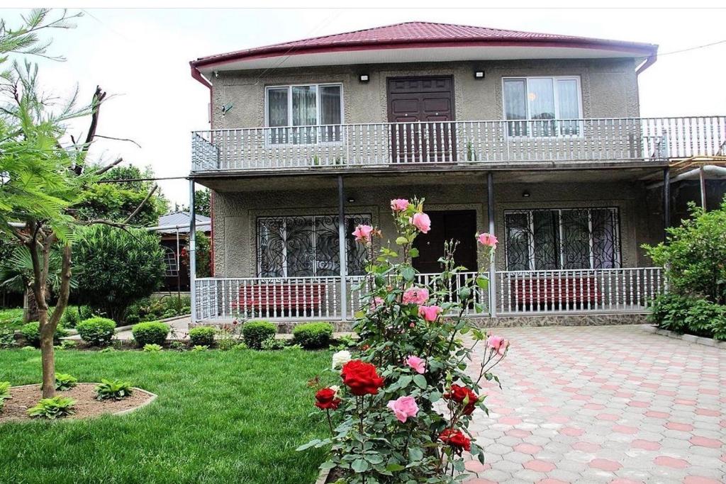 a house with pink roses in the yard at Hotel Oniks in Kutaisi