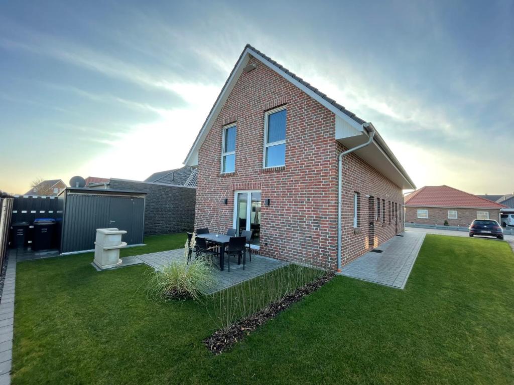 a brick house with a patio and a grass yard at Wangerbrise in Wangerland