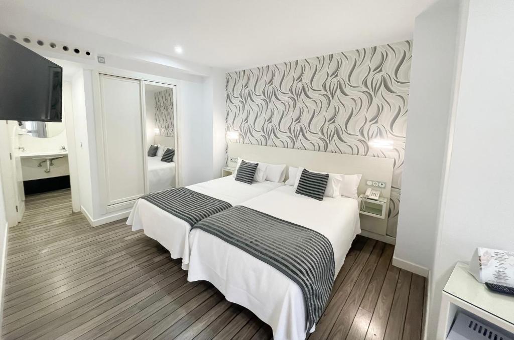 a bedroom with a white bed and a wall at La Boutique Puerta Osario in Córdoba