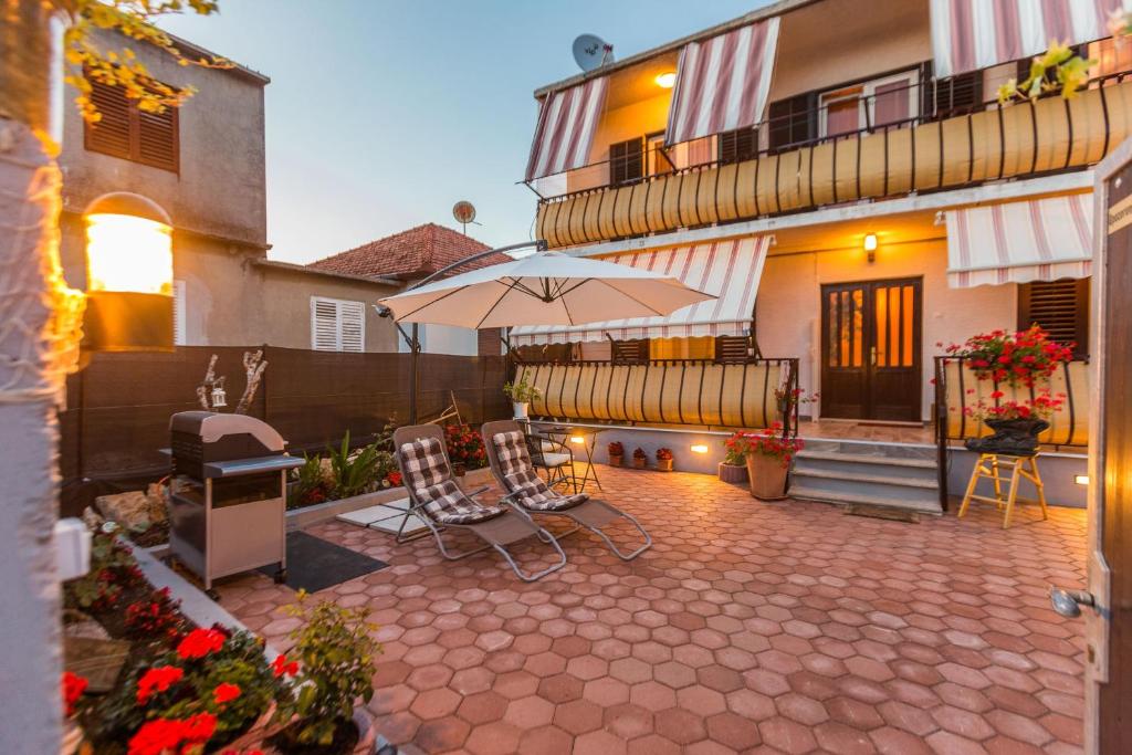 a patio with two chairs and an umbrella in front of a building at Apartments & Rooms Hosana in Zadar