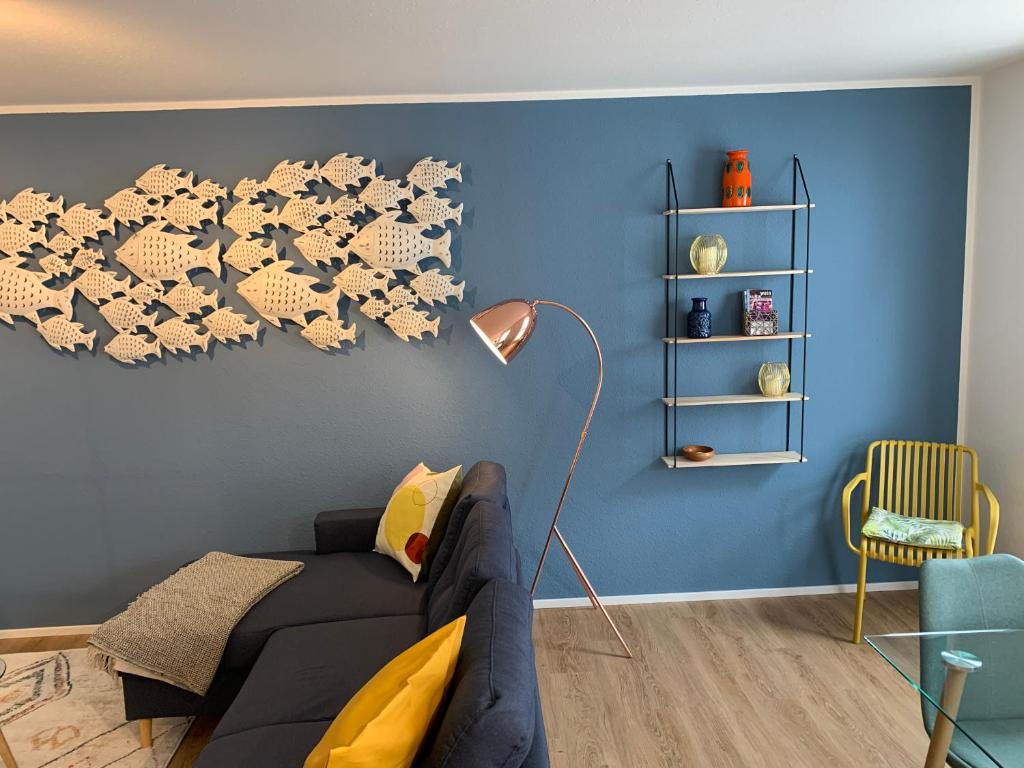 sala de estar con sofá negro y pared azul en Ferienwohnungen Bohner/Ferienwohnung Maria, en Meersburg