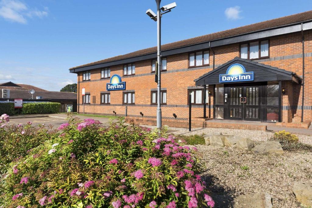 un edificio con un cartel que lee la posada del perro en Days Inn Hotel Warwick South - Southbound M40, en Warwick