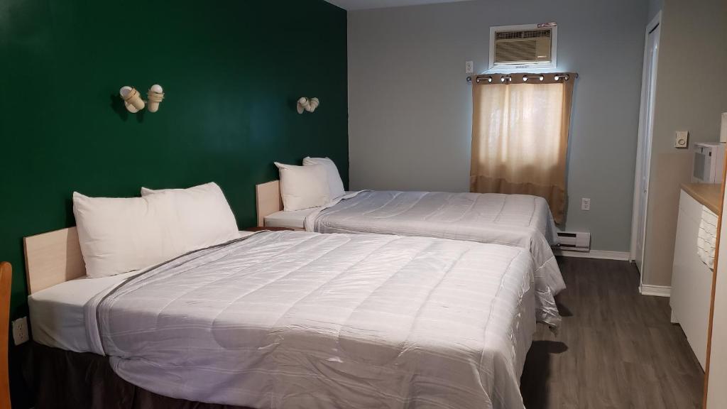 two beds in a room with a green wall at Oakwood Motel in Gravenhurst