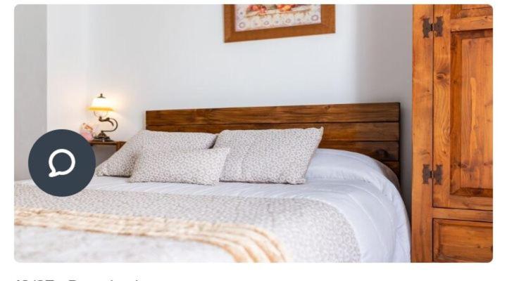 - une chambre avec un lit et une tête de lit en bois dans l'établissement Apartamento en Olvera, à Olvera