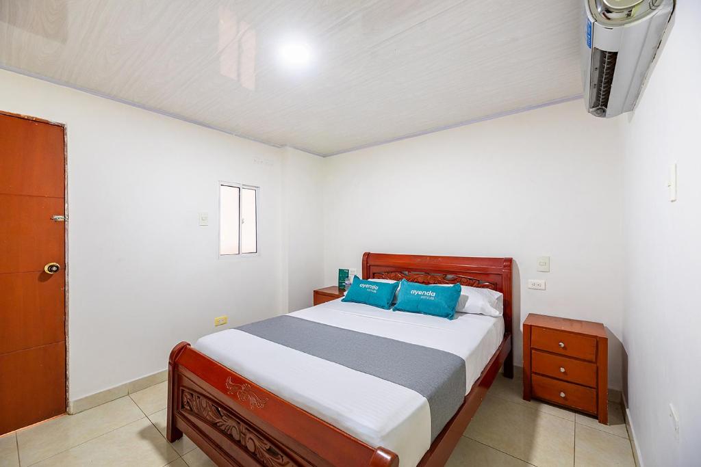 a bedroom with a bed with blue pillows at Hotel Nuevo Yalu in Barranquilla