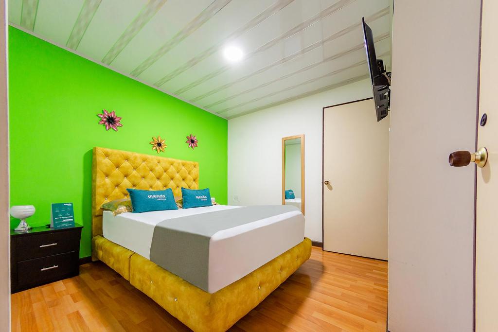 1 dormitorio con 1 cama grande y pared verde en Ayenda Portal del Cable, en Manizales