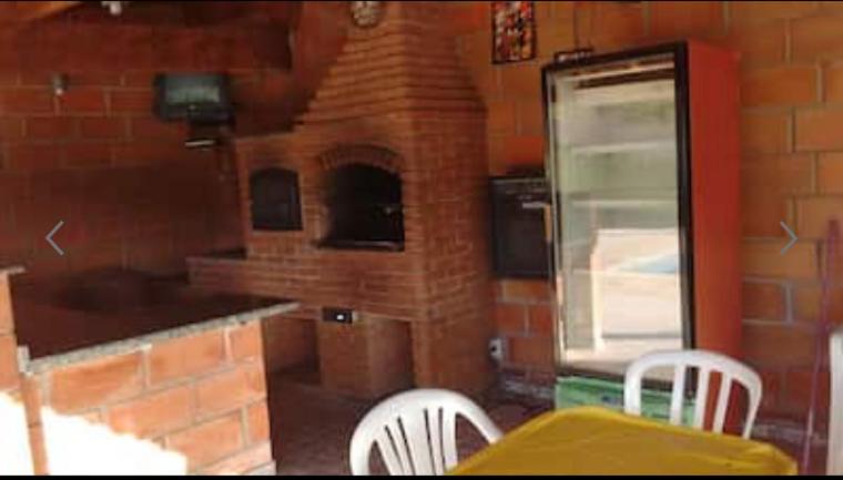 een keuken met een bakstenen oven en een tafel en stoelen bij Chácara Canto Verde Atibaia in Atibaia