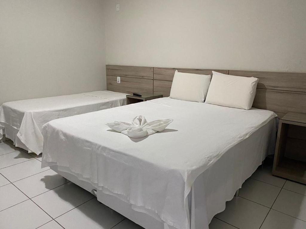 a bedroom with two beds with a white flower on it at Hotel Sabrina in Guanambi