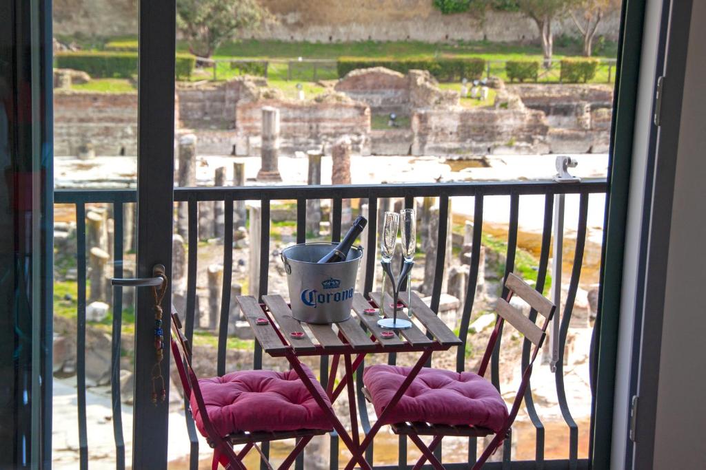 a table with two chairs on a balcony with a view of the ruins at Relais sul Tempio in Pozzuoli