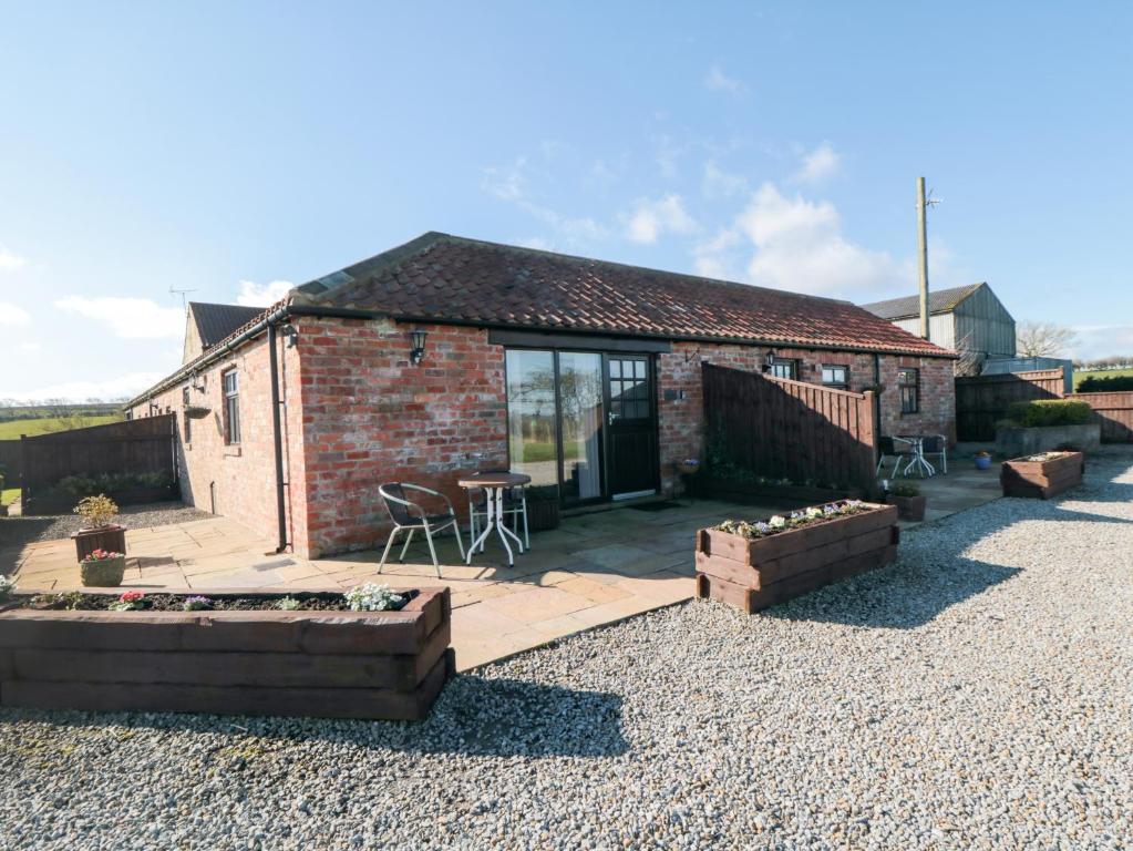 a brick cottage with a patio and a table and chairs at Freeborough in Liverton