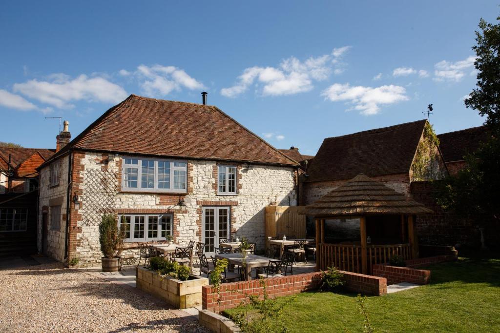 una antigua casa de piedra con cenador en The White Hart, South Harting, en Petersfield