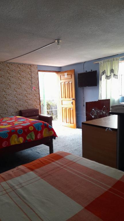 a bedroom with a bed and a television and a door at Hospedaje el Motilon in Quito