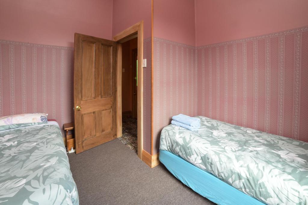two beds in a room with pink walls at Southern Comfort in Invercargill