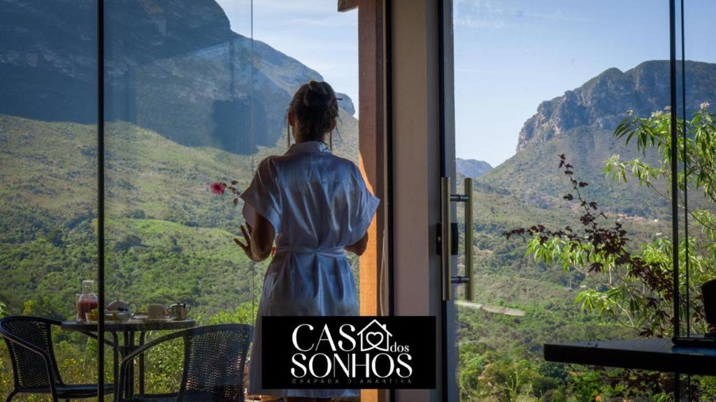 Une femme qui regarde les montagnes par une fenêtre dans l'établissement Casa dos Sonhos, à Ibicoara