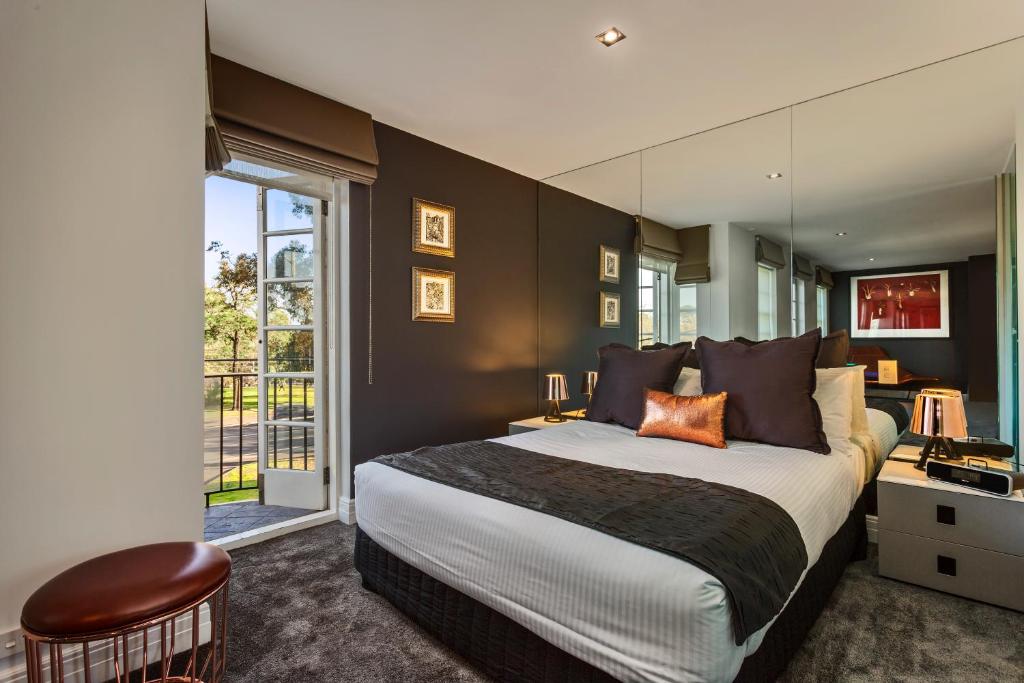 a bedroom with a large bed and a large window at Quest East Melbourne in Melbourne