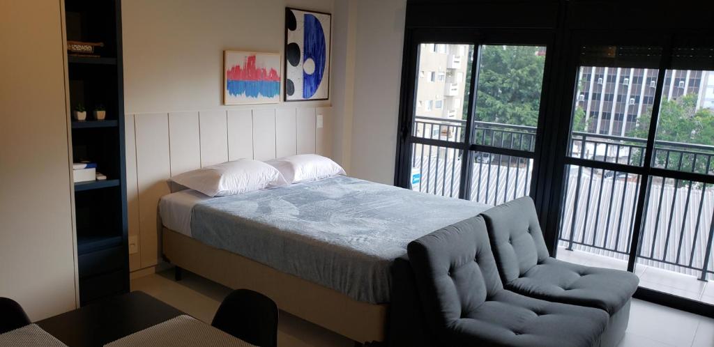 1 dormitorio con 1 cama, 1 silla y ventanas en 68 Brand-new studio next to Paulista Av, fast wifi, en São Paulo