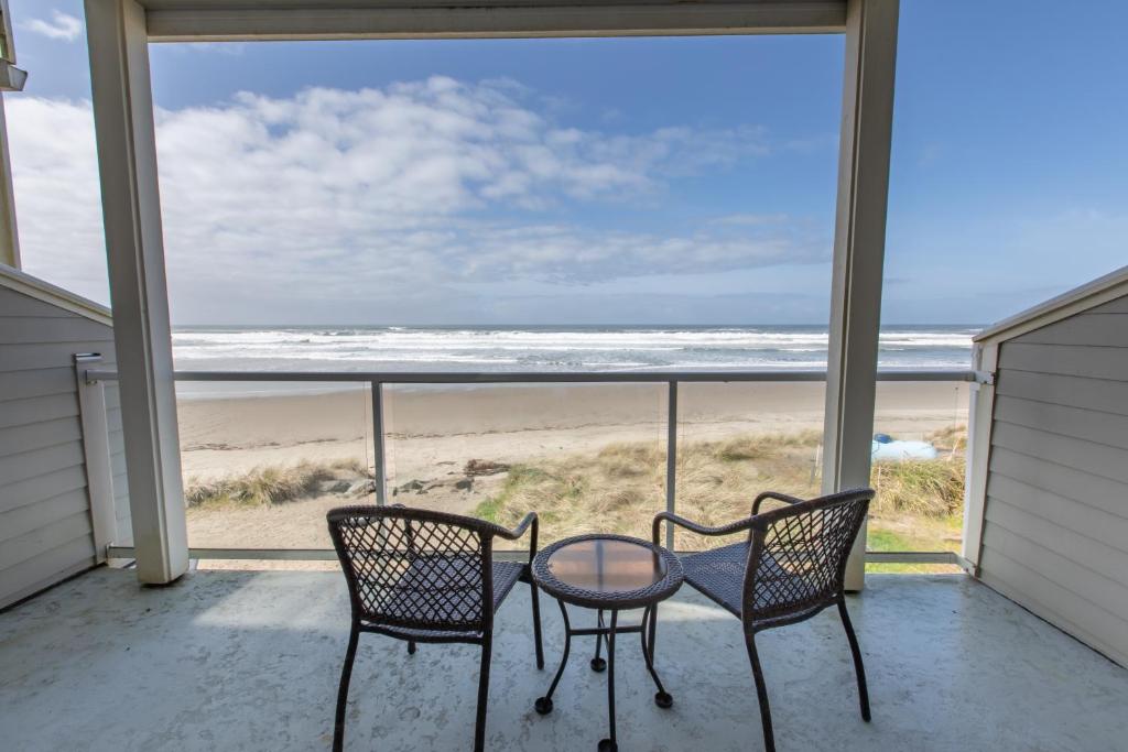 a balcony with two chairs and a table with a view of the beach at Rockaway beach vibes,Waterfront Oceanfront Rockaway Beach House near Downtown,WIFI, Washer Dryer in Rockaway Beach