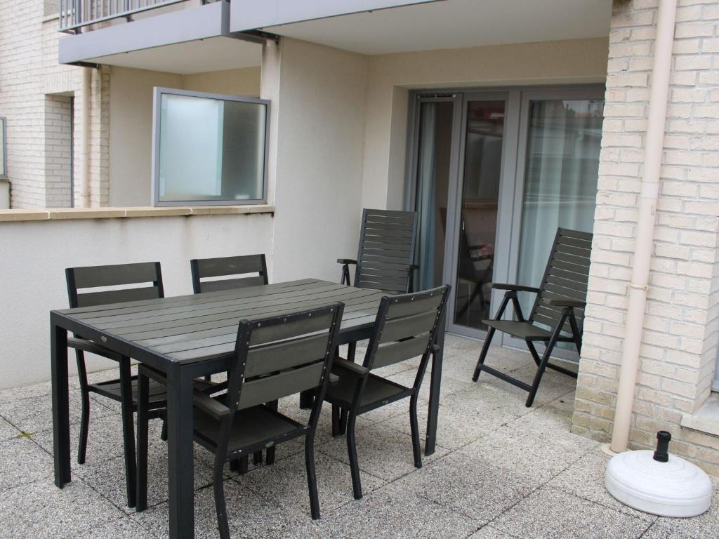 Une table et des chaises en bois sont disponibles sur la terrasse. dans l'établissement Nice apartment with terrace near the sea, à Bray-Dunes