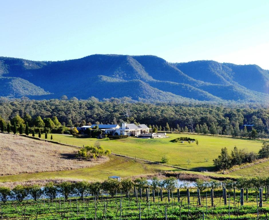 a view of a farm with mountains in the background at Grapevines Boutique Accommodation in Pokolbin
