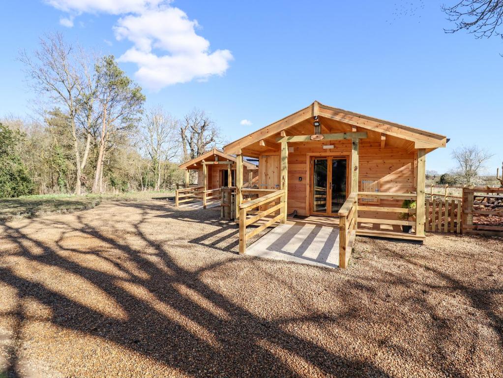 a wooden cabin with a gate and a fence at Clover Lodge in Leiston