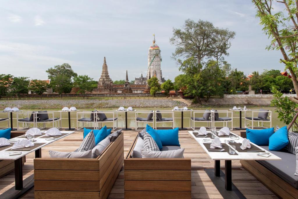 a restaurant with white tables and blue pillows at Sala Ayutthaya in Phra Nakhon Si Ayutthaya