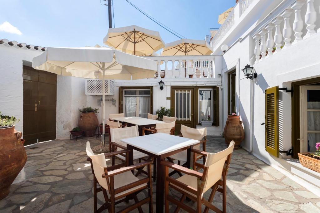 a patio with tables and chairs and umbrellas at Villa Kalomira in Spetses