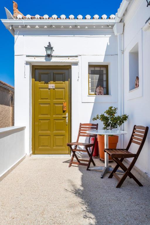 two chairs sitting in front of a yellow door at Villa Kalomira in Spetses