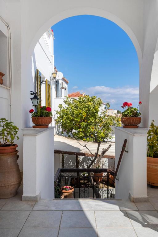 an archway with potted plants and a table on a balcony at Villa Kalomira in Spetses