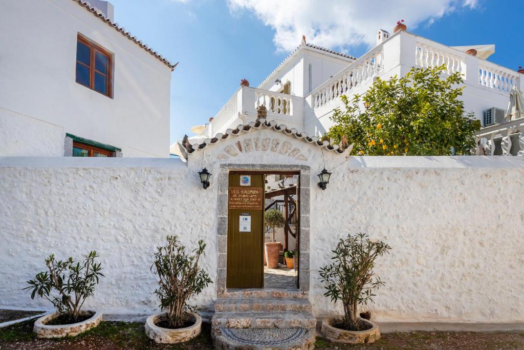 un edificio bianco con una porta e alcune piante di Villa Kalomira a Spetses