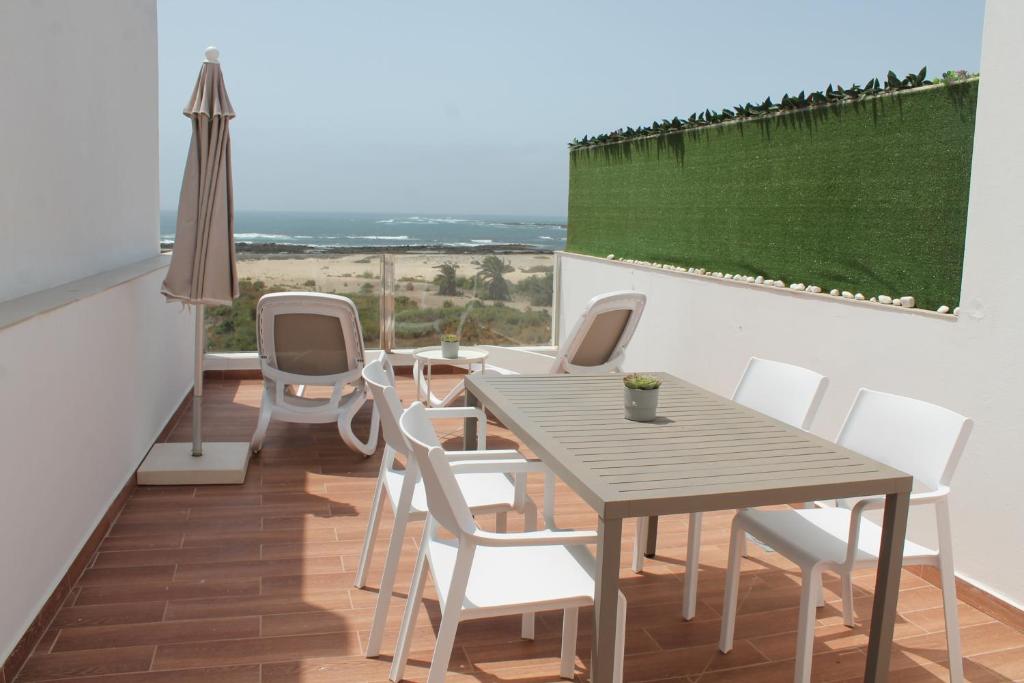 a balcony with a wooden table and white chairs at Apartamentos Tocororo in Cotillo