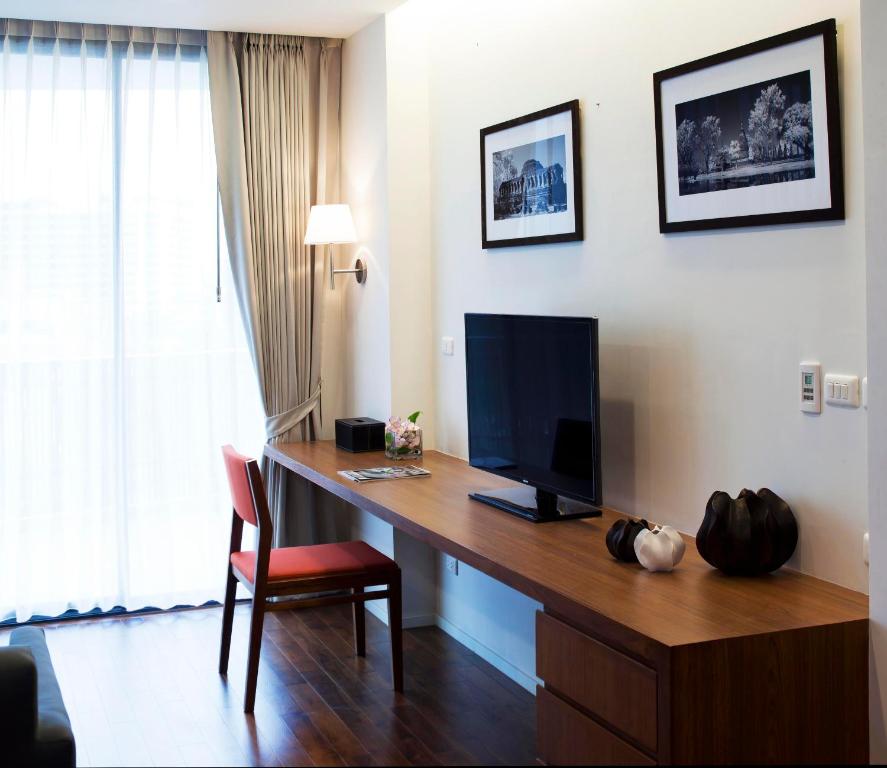 A narrow desk beside a curtained window doubles as a television console in this guest room.