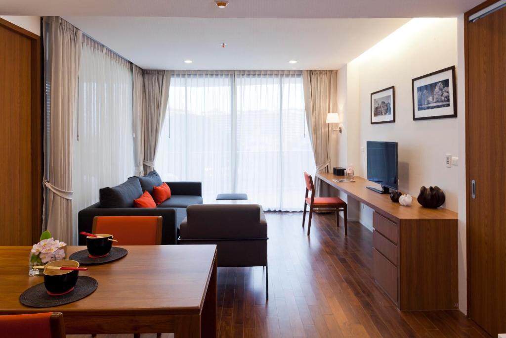 A furnished living room with a long work surface and full-height curtained windows.
