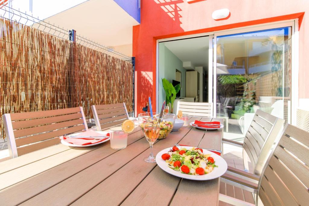 une table en bois avec des assiettes de nourriture sur un balcon dans l'établissement SELECT'SO HOME - Résidence Le Poséidon - Mazet en Duplex - Prestations de qualité & Services Hôteliers - POS-G, à Bormes-les-Mimosas