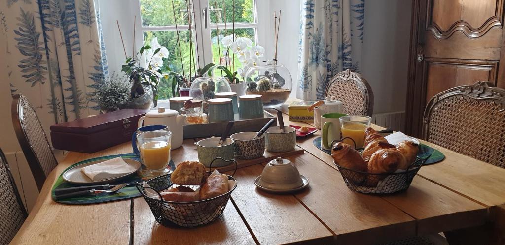 a wooden table with breakfast foods and orange juice at Le champ de l&#39;eau in Crécy-la-Chapelle