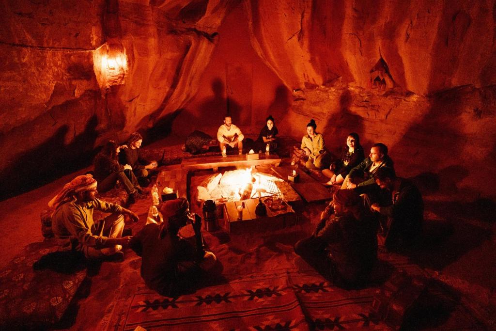 a group of people sitting around a fire in a cave at Bedouin Nights Camp in Wadi Rum