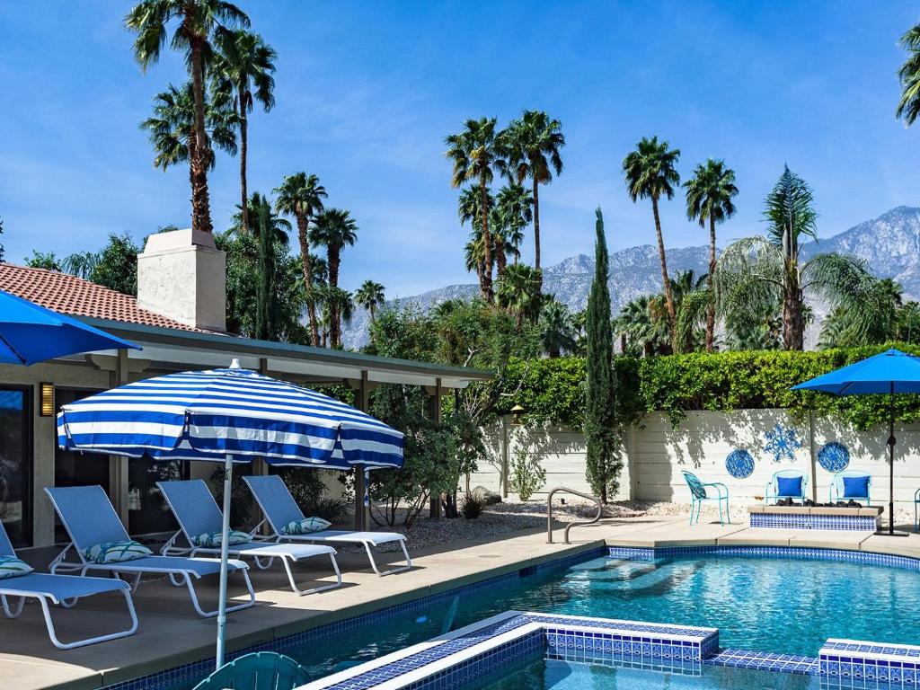a pool with chairs and umbrellas and palm trees at Andiamo al Sole in Palm Springs