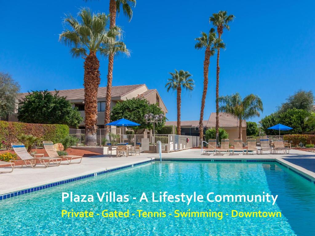 a swimming pool with chairs and palm trees at Double Down Hideaway in Palm Springs