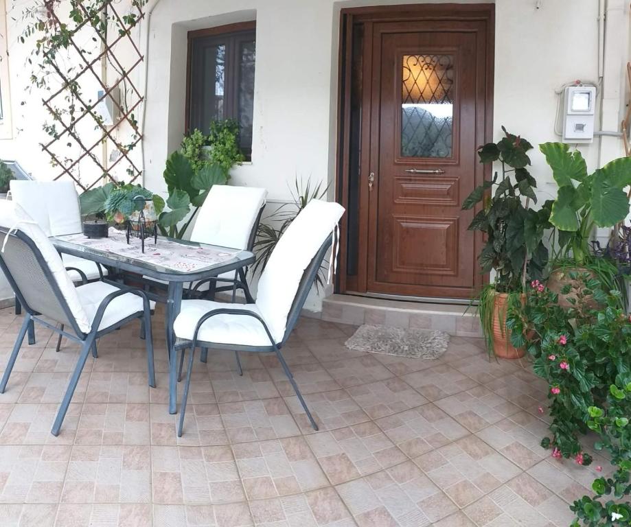 d'une terrasse avec une table, des chaises et une porte. dans l'établissement Arhontiko Katerina Spili, à Árdhaktos