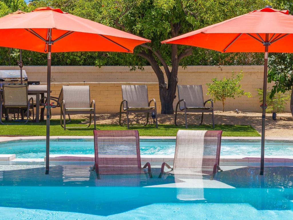 twee stoelen en parasols naast een zwembad bij Boo Boo's Hideaway in Palm Springs