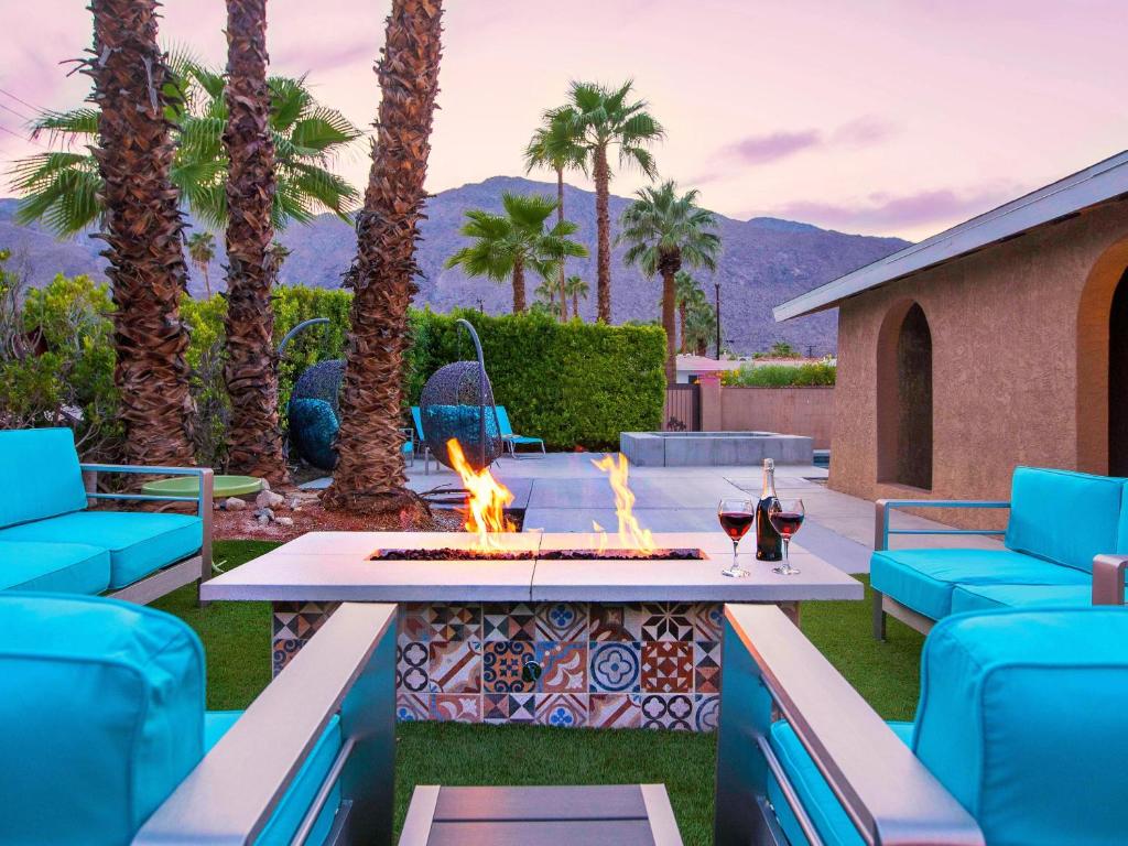 a patio with a fire pit and palm trees at Sunny Palms at Warm Sands in Palm Springs