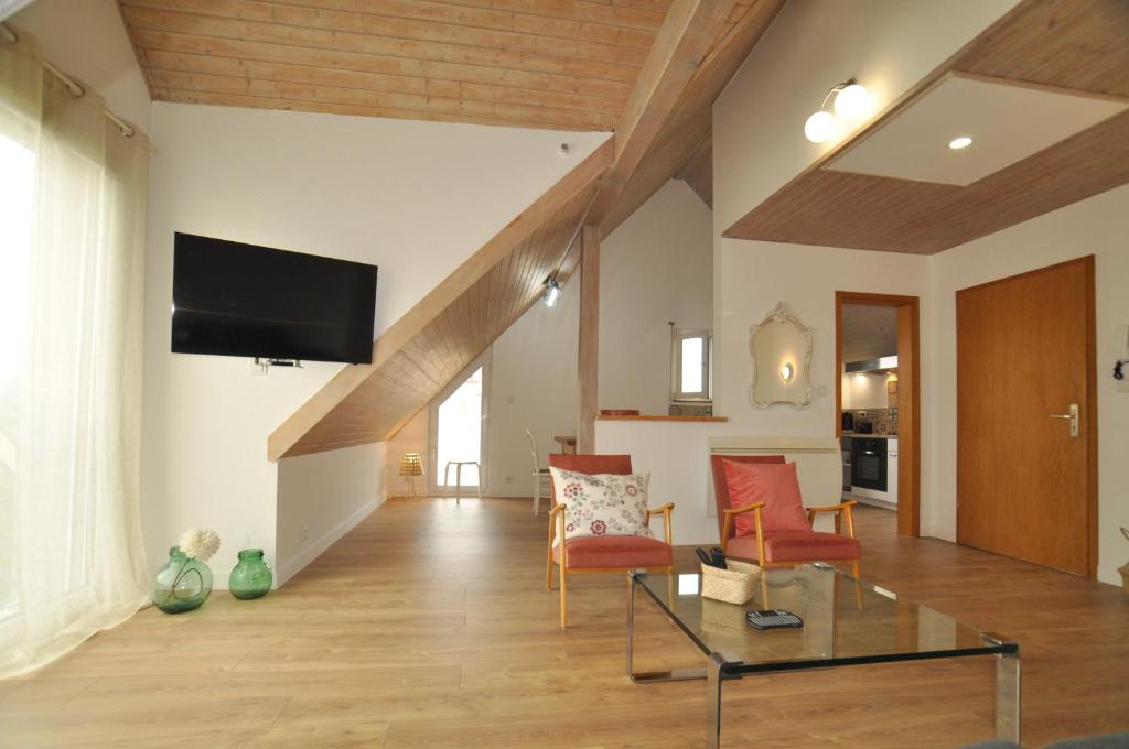 a living room with a flat screen tv on the wall at L'Hirondelle - Charming flat - in Blotzheim