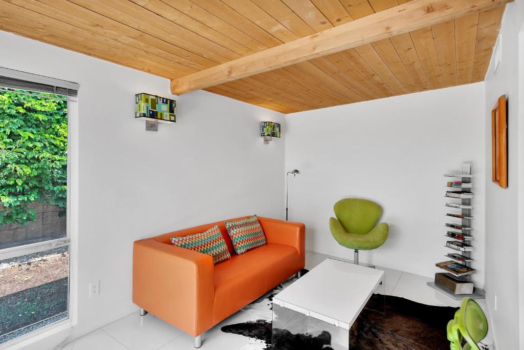 um sofá laranja numa sala de estar com tecto de madeira em Papillon Palm Springs em Palm Springs