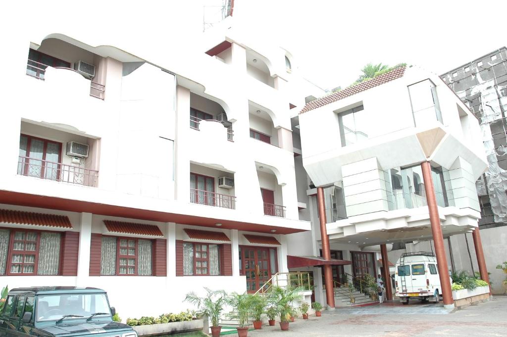 Un bâtiment blanc avec une voiture garée devant. dans l'établissement Hotel Gnanam, à Thanjavur