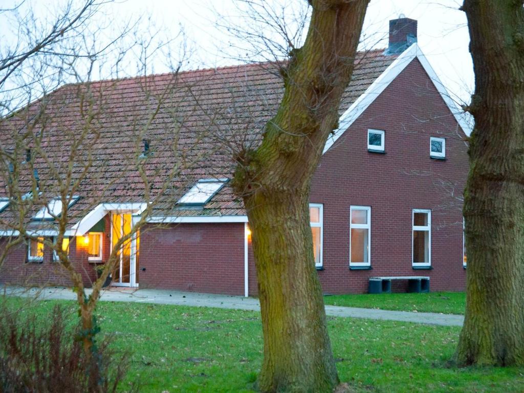 a large red brick house with two trees in front at Landzicht 05 in Ter Apel